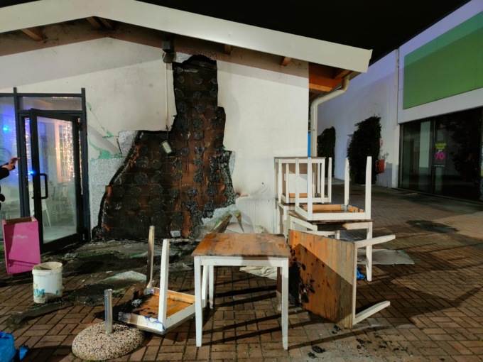In fiamme sedie, ombrellone e parte esterna di un bar
