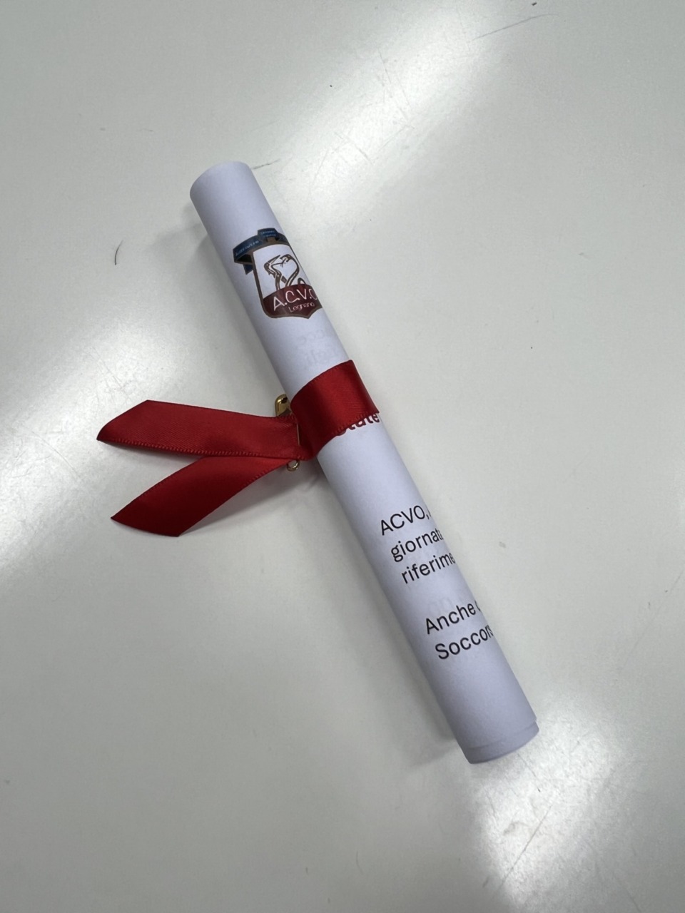 Un fiocco rosso e un volantino con i numeri antiviolenza distribuiti in ospedale dalle volontarie Acvo