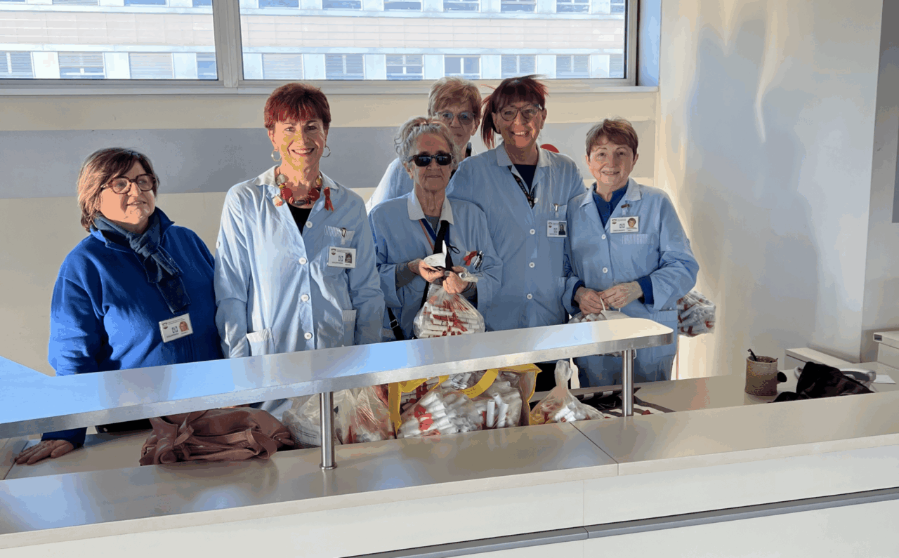 Un fiocco rosso e un volantino con i numeri antiviolenza distribuiti in ospedale dalle volontarie Acvo