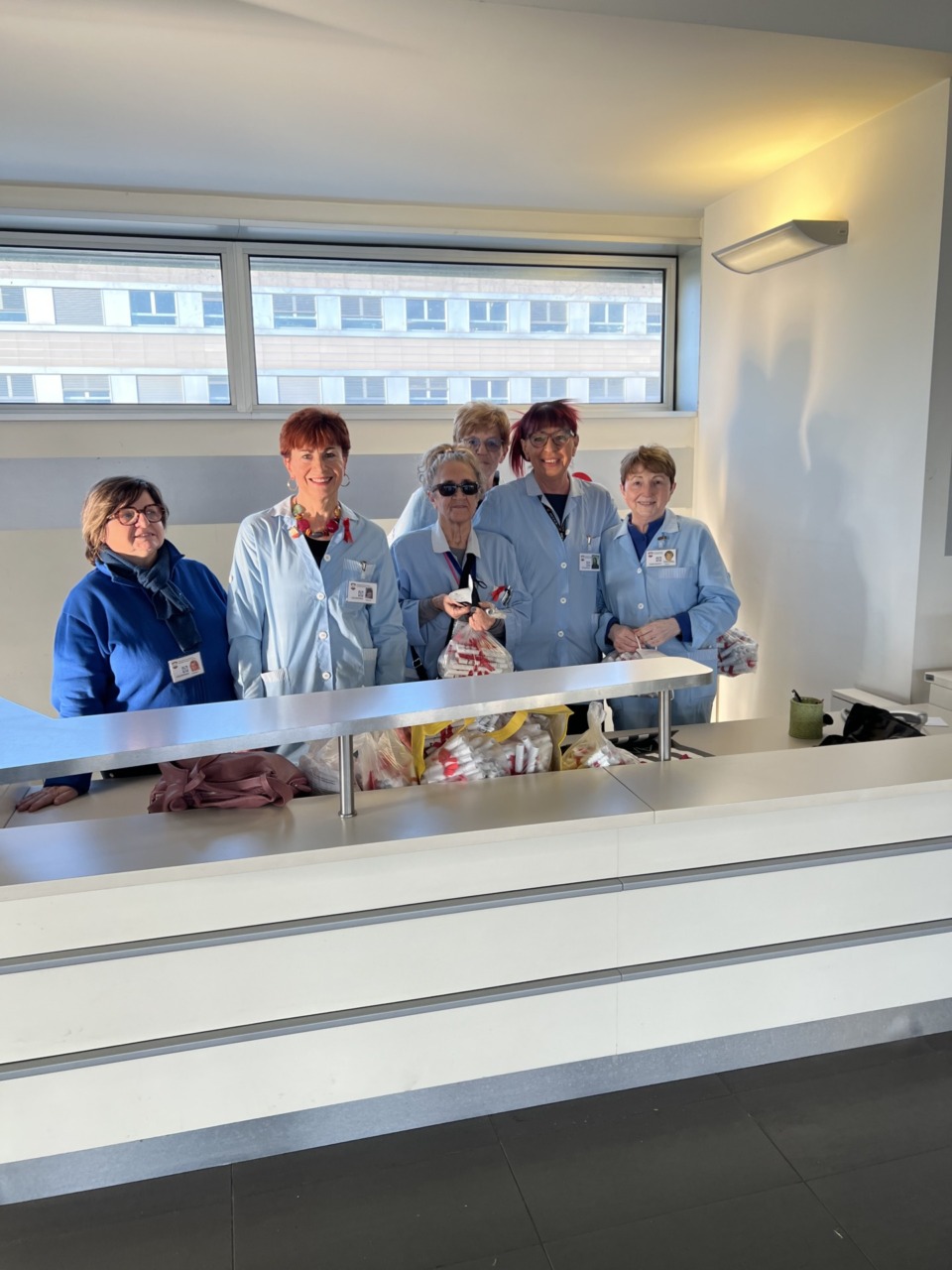 Un fiocco rosso e un volantino con i numeri antiviolenza distribuiti in ospedale dalle volontarie Acvo